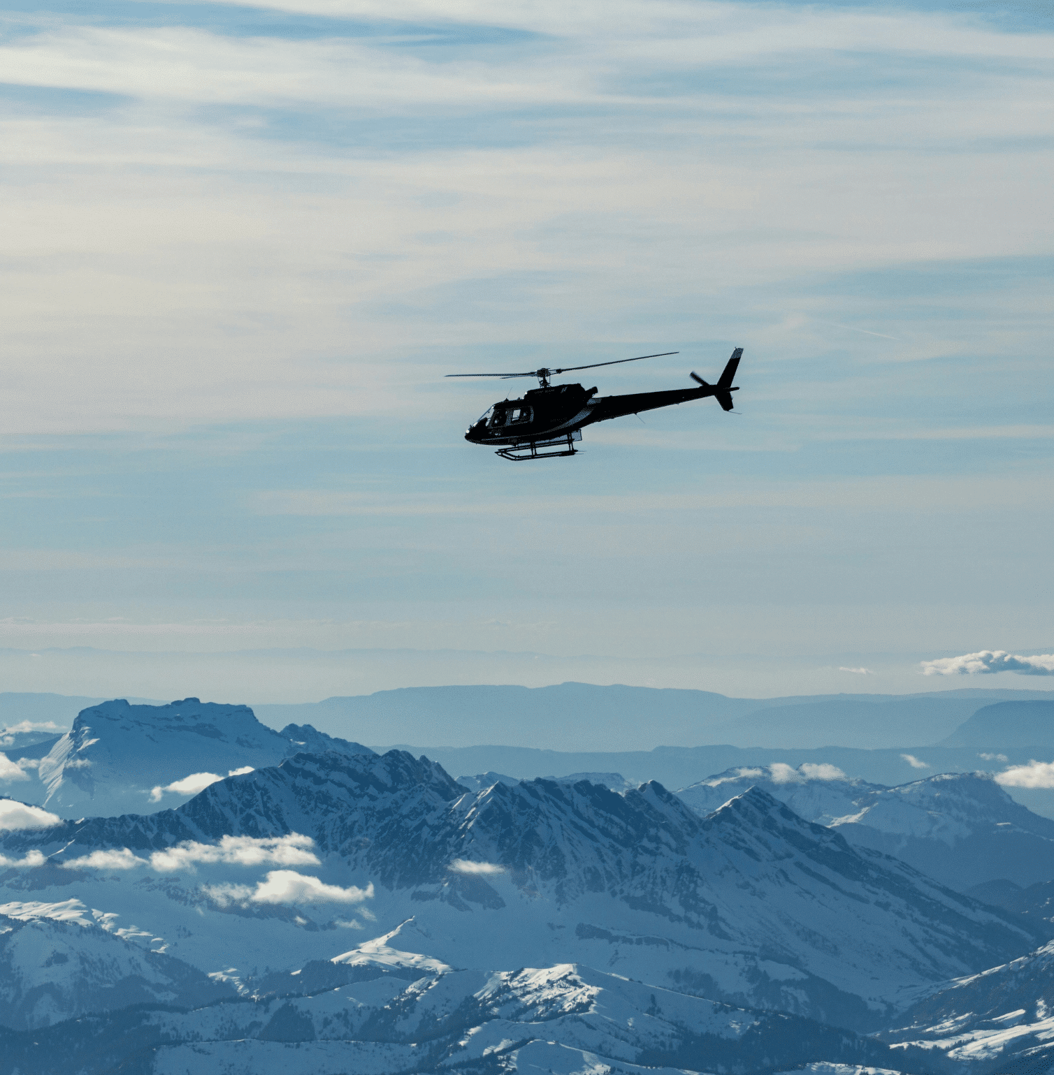 Helicopter flying over snowy mountains in the French Alps