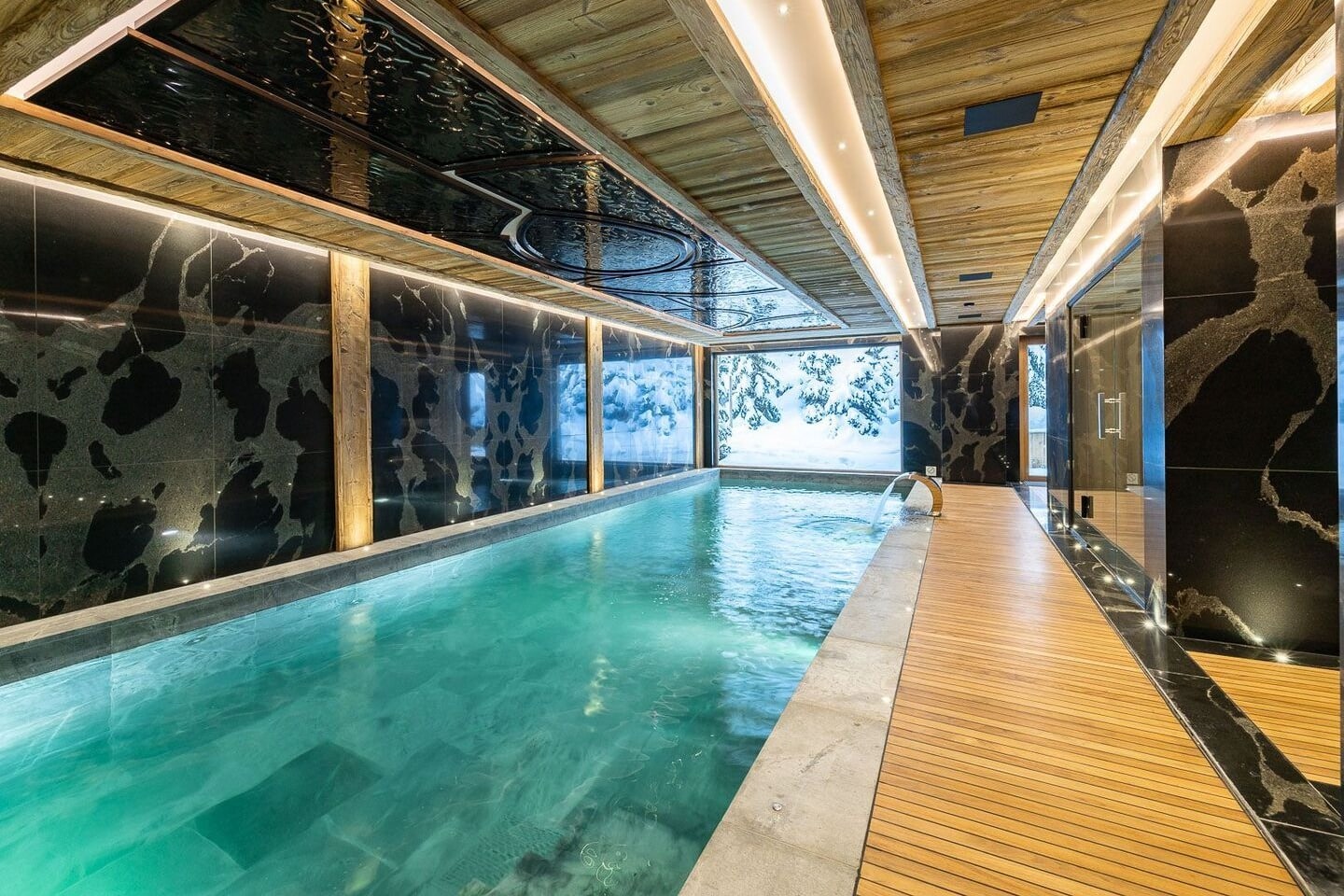 Indoor pool with marble walls and wooden deck in a luxury Courchevel apartment residence