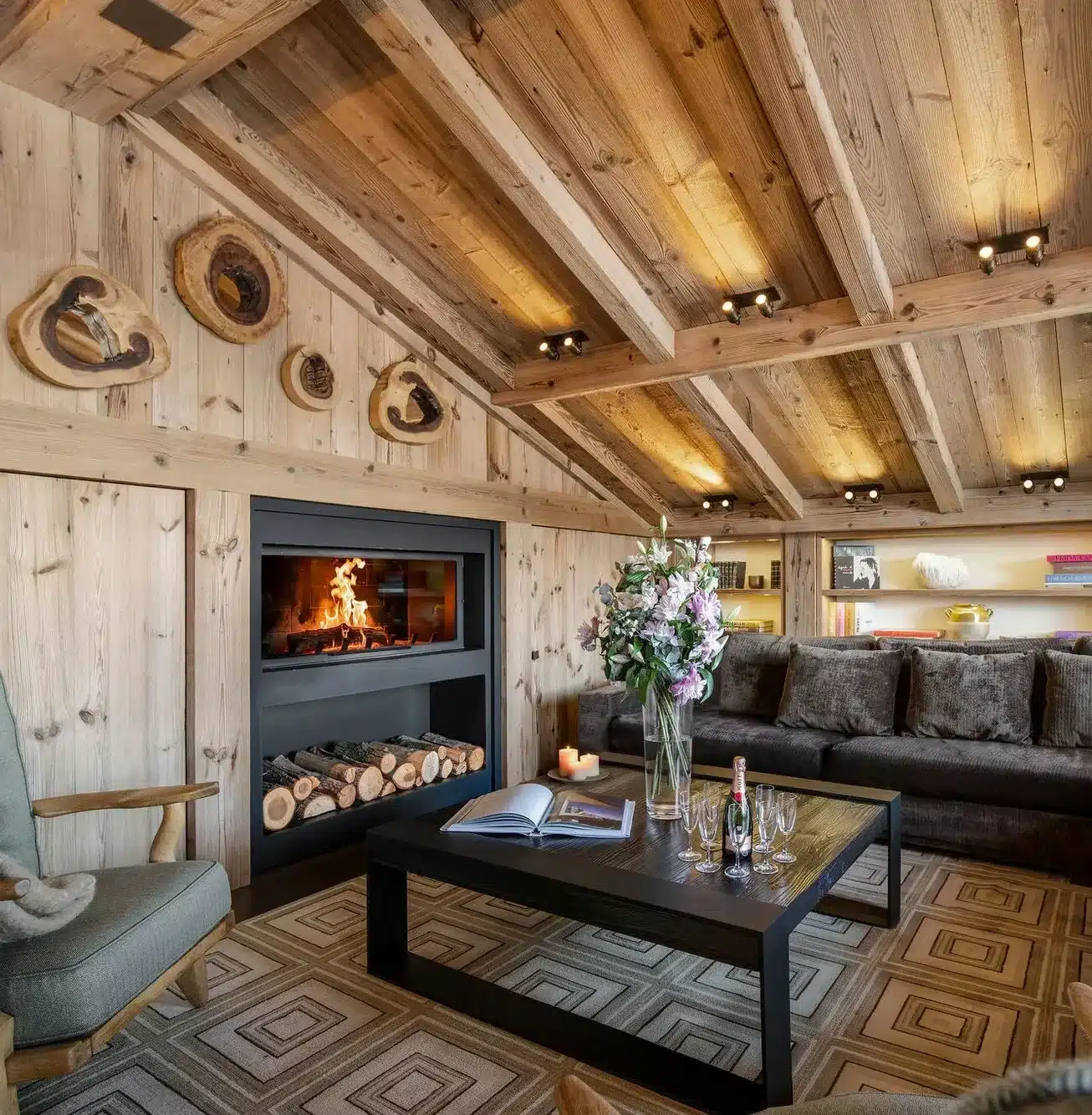 Cozy chalet living room with fireplace, wood paneling, and fresh flowers