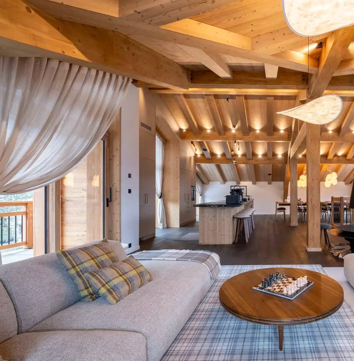 Open-plan living room and kitchen with exposed wood beams in a luxury Courchevel chalet