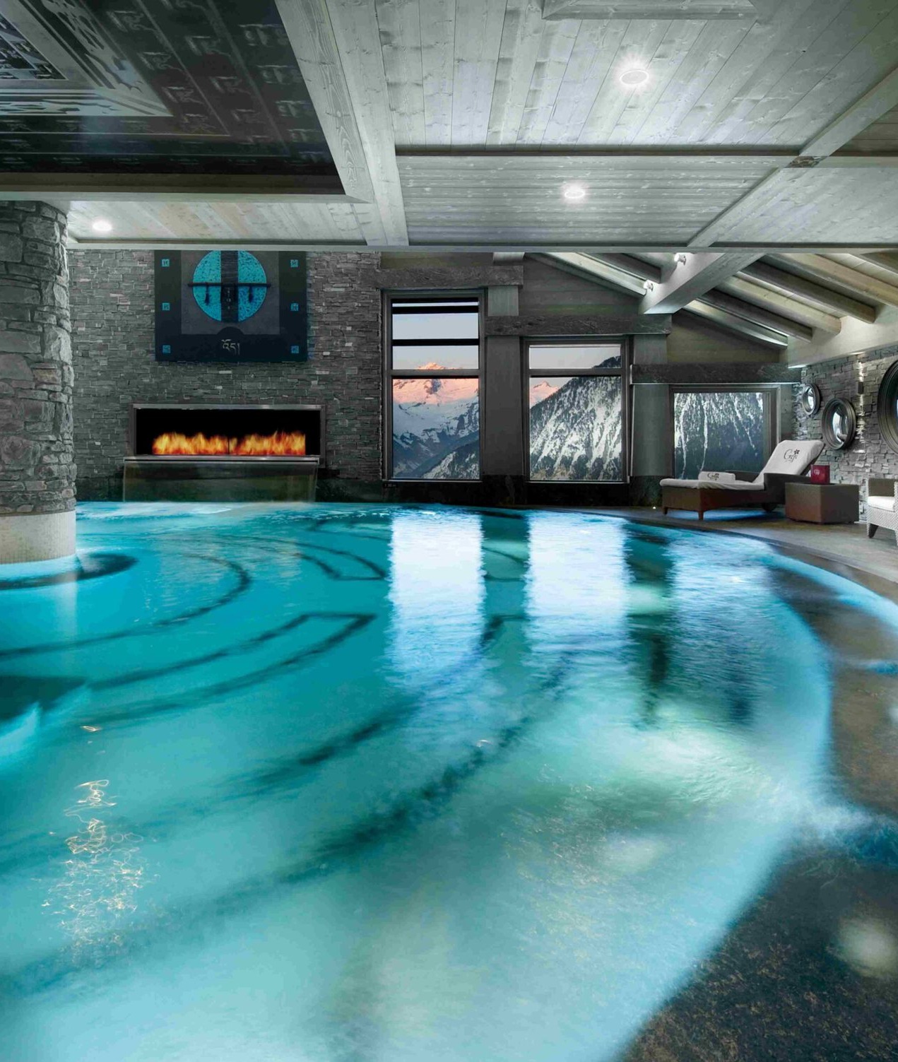 Indoor swimming pool with fireplace and mountain views at K2 Palace Courchevel