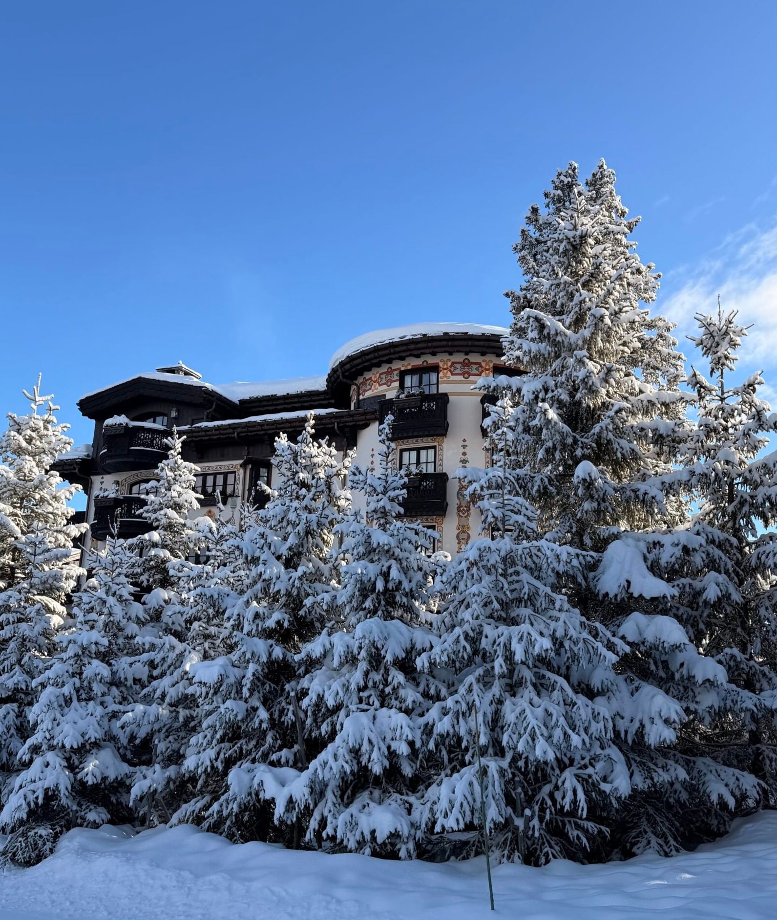 Snow-covered exterior of Les Airelles luxury hotel surrounded by frosted pine trees in Courchevel