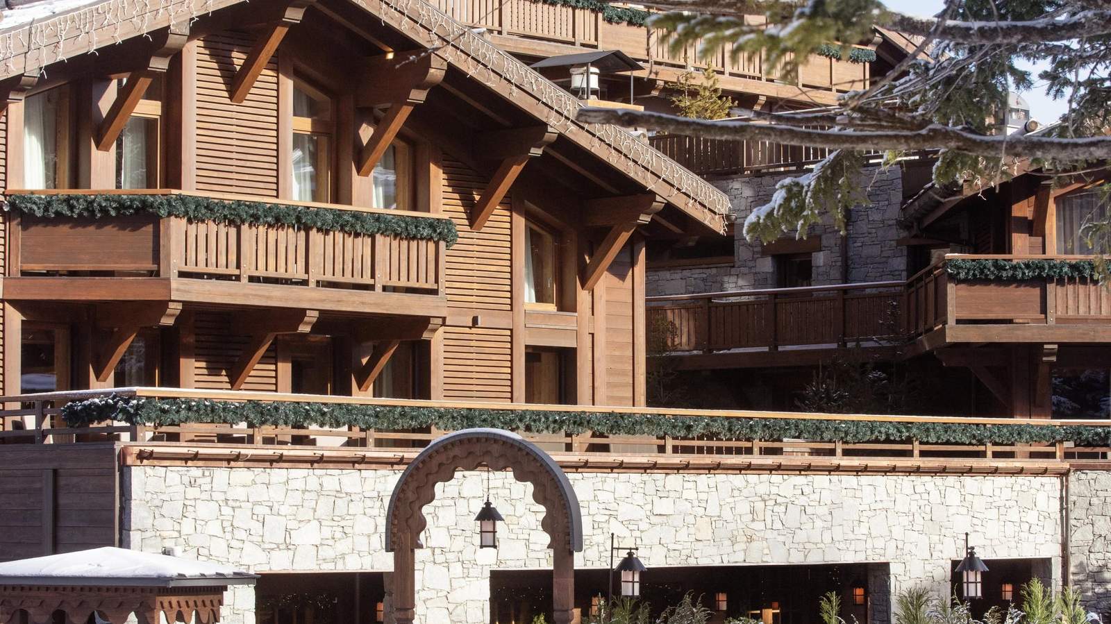 Wooden chalet facade and stone archway of Barrière Les Neiges, home of Loulou, Courchevel 1850